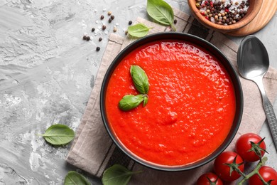 Photo of Delicious tomato cream soup served on grey textured table, flat lay. Space for text