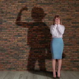 Image of Businesswoman and shadow of strong muscular lady behind her on brick wall. Concept of inner strength