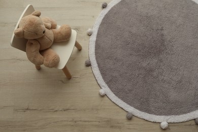 Photo of Stylish soft rug and chair with toy bear on floor, top view