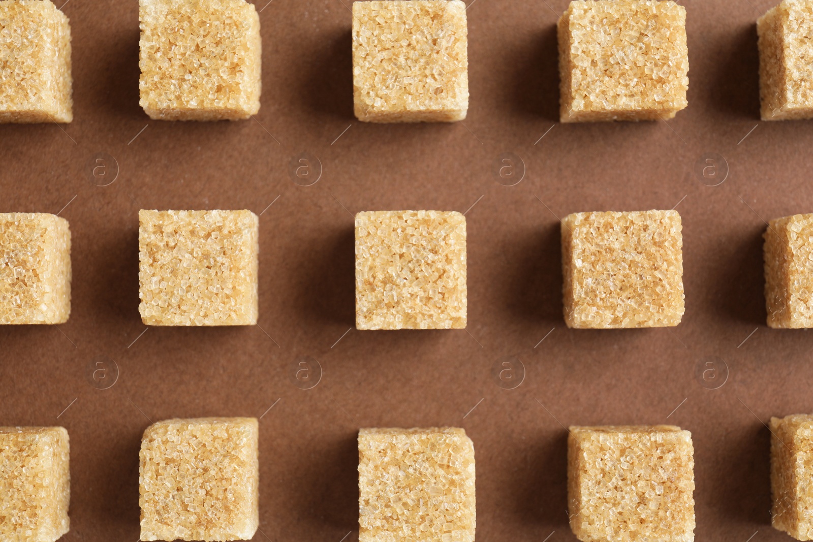 Photo of Brown sugar cubes on color background, top view