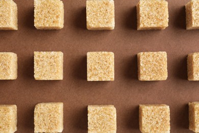 Brown sugar cubes on color background, top view