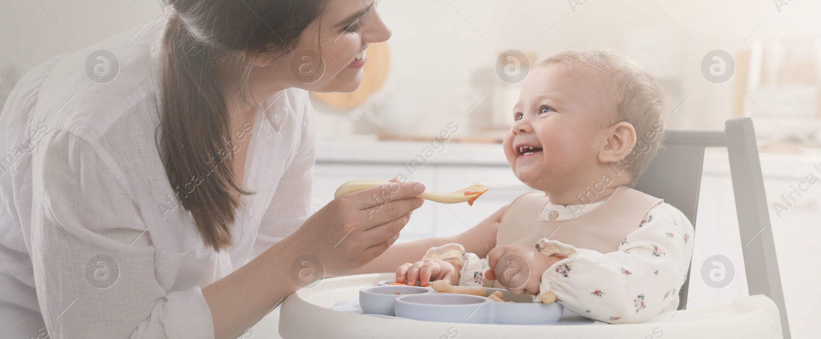 Image of Mother feeding her cute little baby in kitchen. Banner design