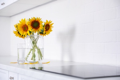 Bouquet of beautiful sunflowers on counter in kitchen. Space for text