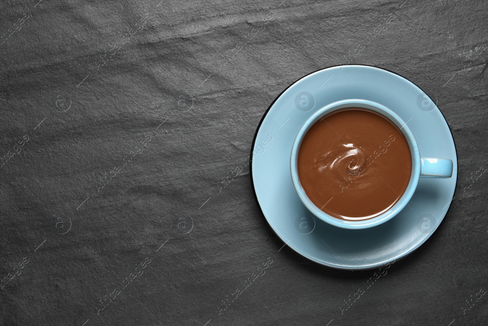 Photo of Yummy hot chocolate in cup on black table, top view. Space for text