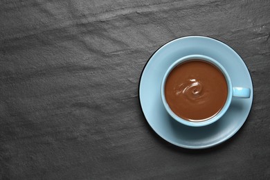 Yummy hot chocolate in cup on black table, top view. Space for text