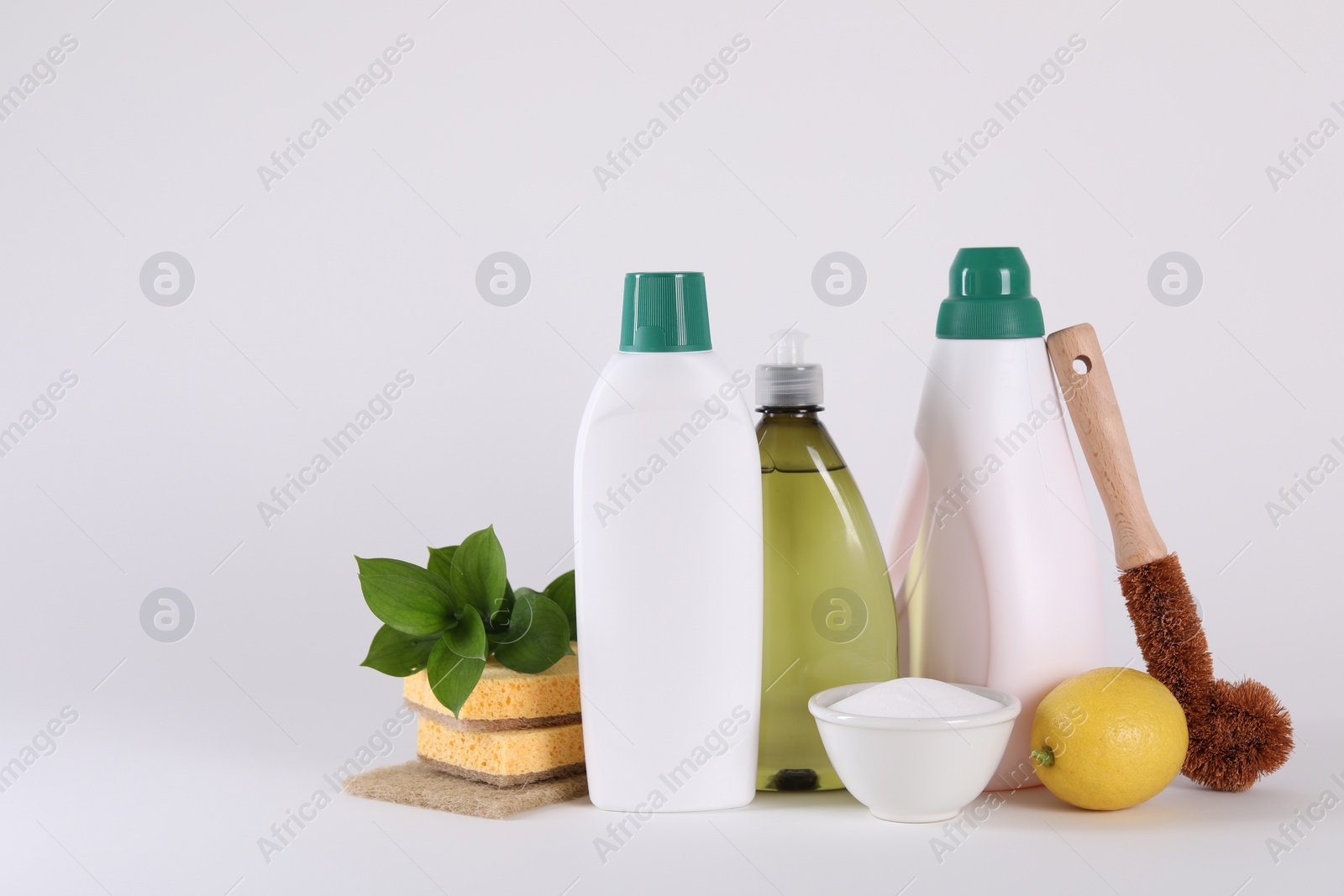 Photo of Bottles of cleaning product, brush, sponges and lemon isolated on white