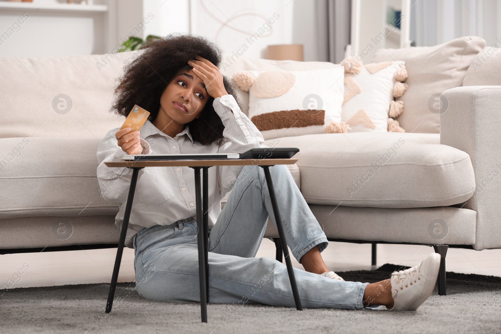 Photo of Confused woman with calculator and credit card planning budget at home. Debt problem