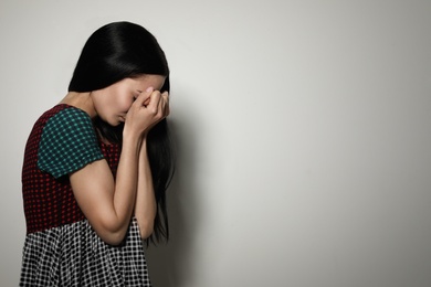 Photo of Upset young woman crying against light background. Space for text