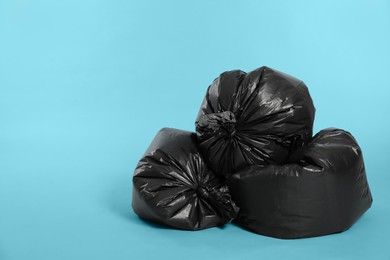 Photo of Trash bags full of garbage on light blue background. Space for text