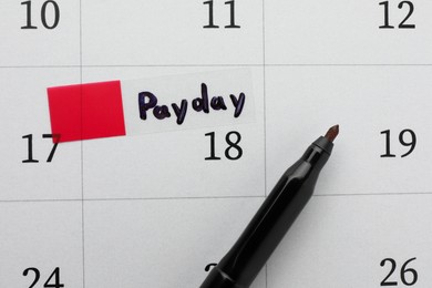 Photo of Black felt pen on calendar page with marked payday date, top view