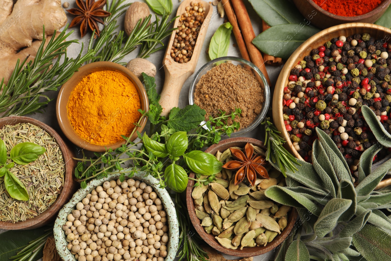 Photo of Different herbs and spices on grey table, flat lay