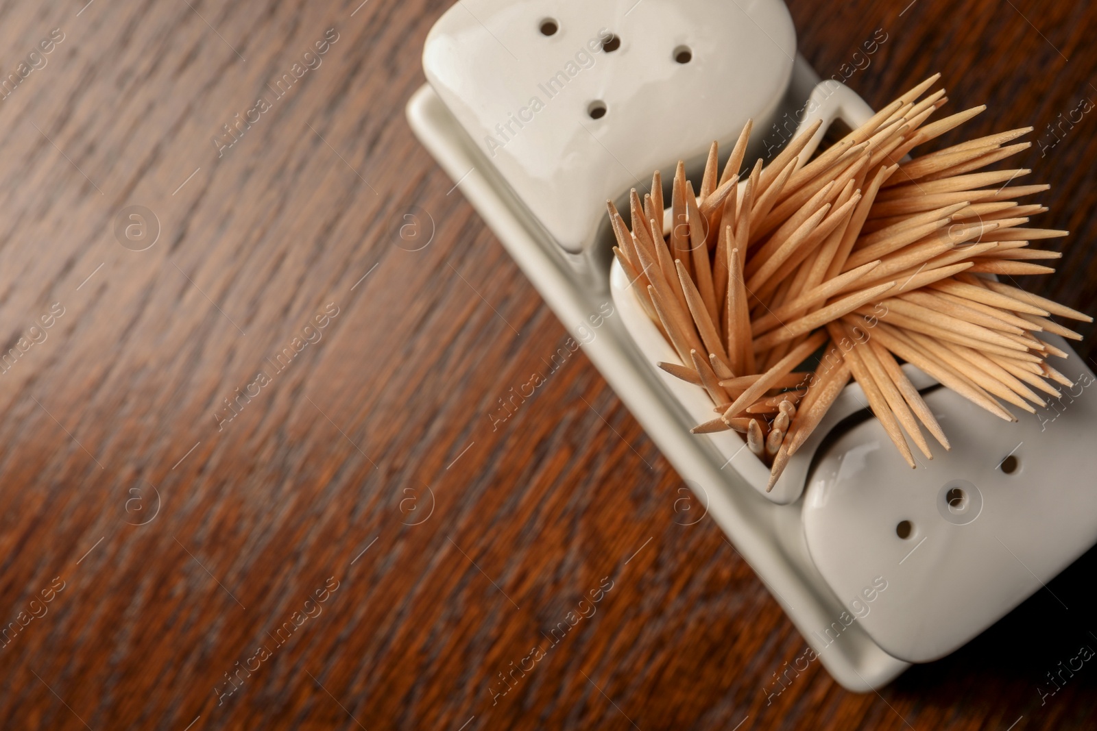 Photo of Holder with salt, pepper and toothpicks on wooden table, top view. Space for text