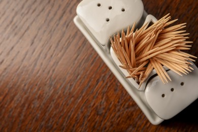 Photo of Holder with salt, pepper and toothpicks on wooden table, top view. Space for text