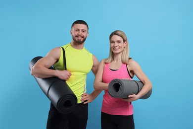 Photo of Athletic people with fitness mats on light blue background