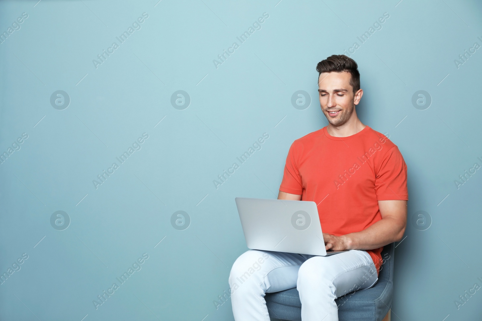Photo of Man in casual clothes with laptop on color background