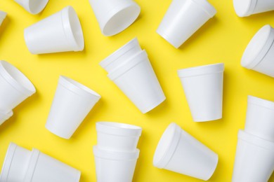 Photo of White styrofoam cups on yellow background, flat lay