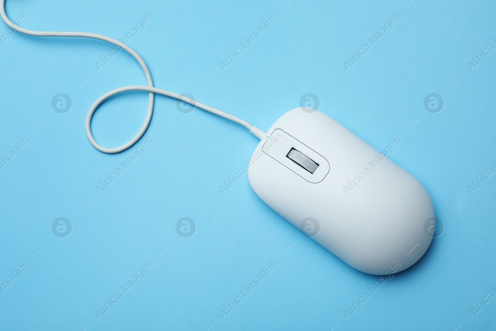 Photo of Wired computer mouse on light blue background, top view