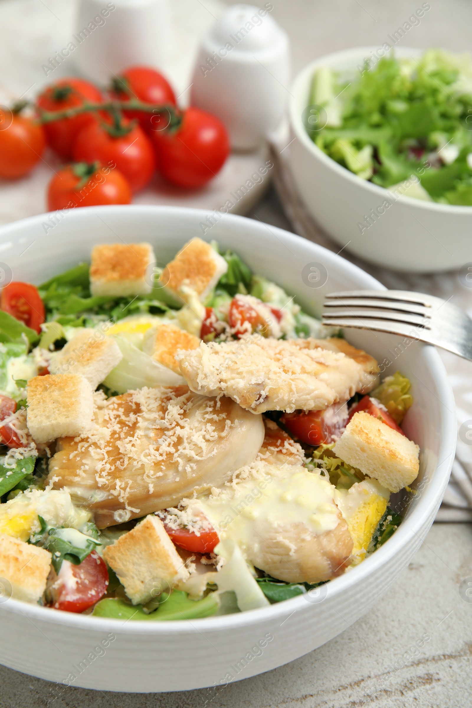 Photo of Delicious fresh Caesar salad in bowl on light grey table, closeup