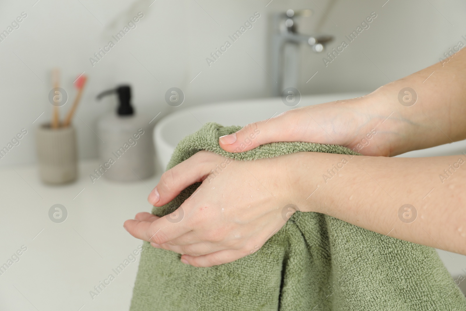 Photo of Woman wiping hands with towel in bathroom, closeup