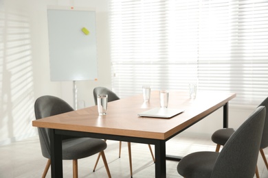 Photo of Conference room interior with wooden table and flipchart