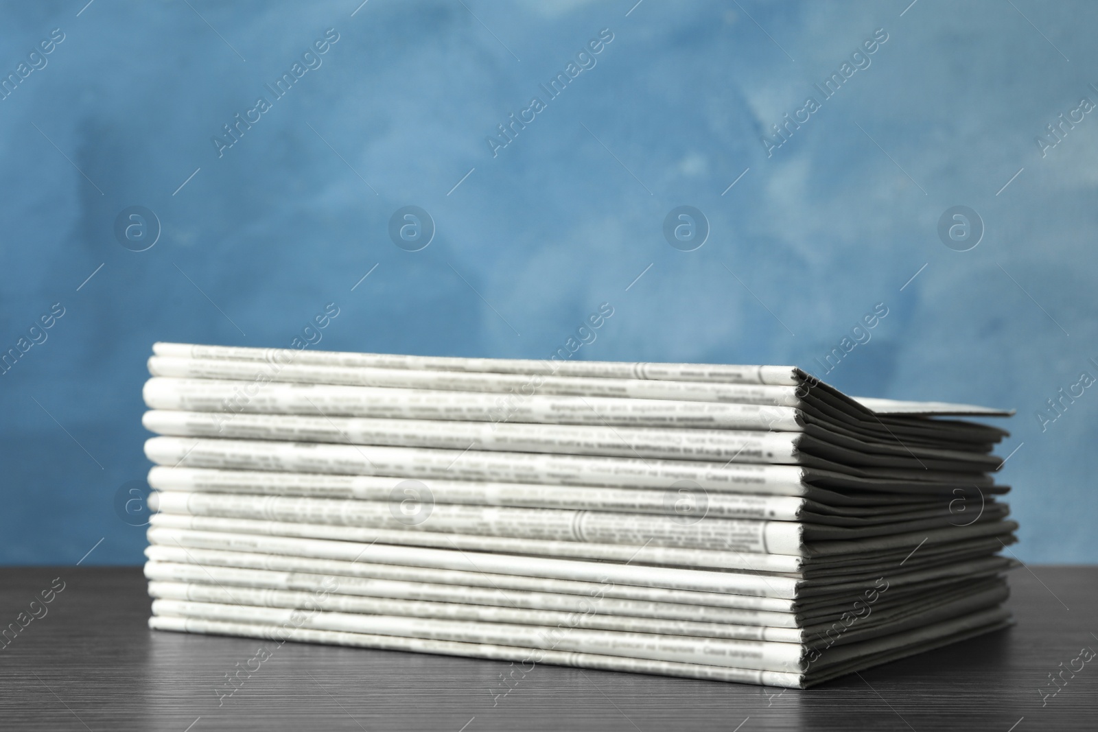 Photo of Stack of newspapers on blue background. Journalist's work