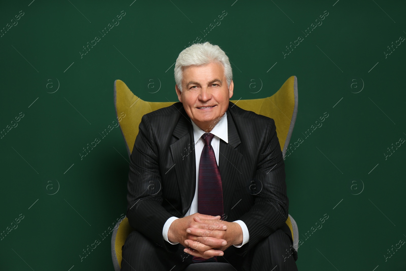 Photo of Happy mature businessman sitting in armchair against green background