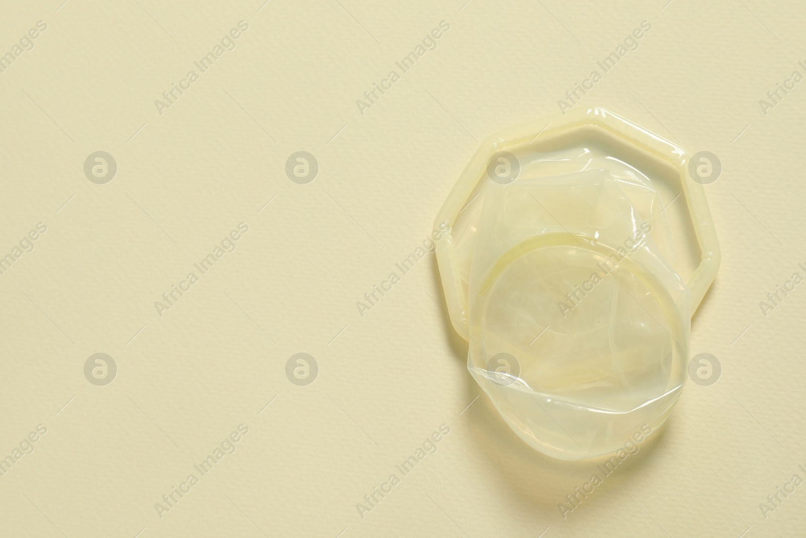 Photo of Female condom on beige background, top view and space for text. Safe sex