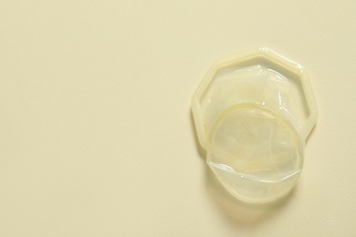 Female condom on beige background, top view and space for text. Safe sex