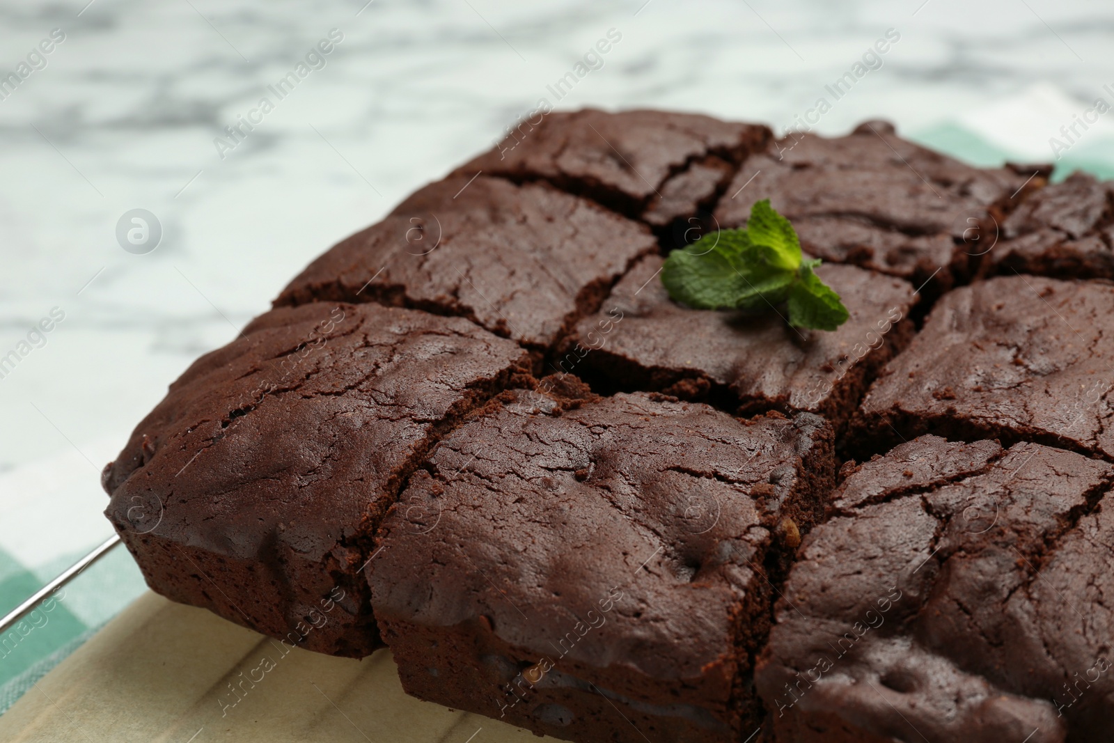 Photo of Cooling rack with delicious freshly baked brownies on white table, closeup