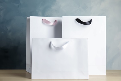 Photo of Paper shopping bags on table against color background. Mock up for design