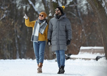 Photo of Happy young couple walking in snowy park on winter day