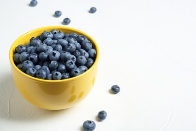 Photo of Crockery with juicy and fresh blueberries on white table. Space for text