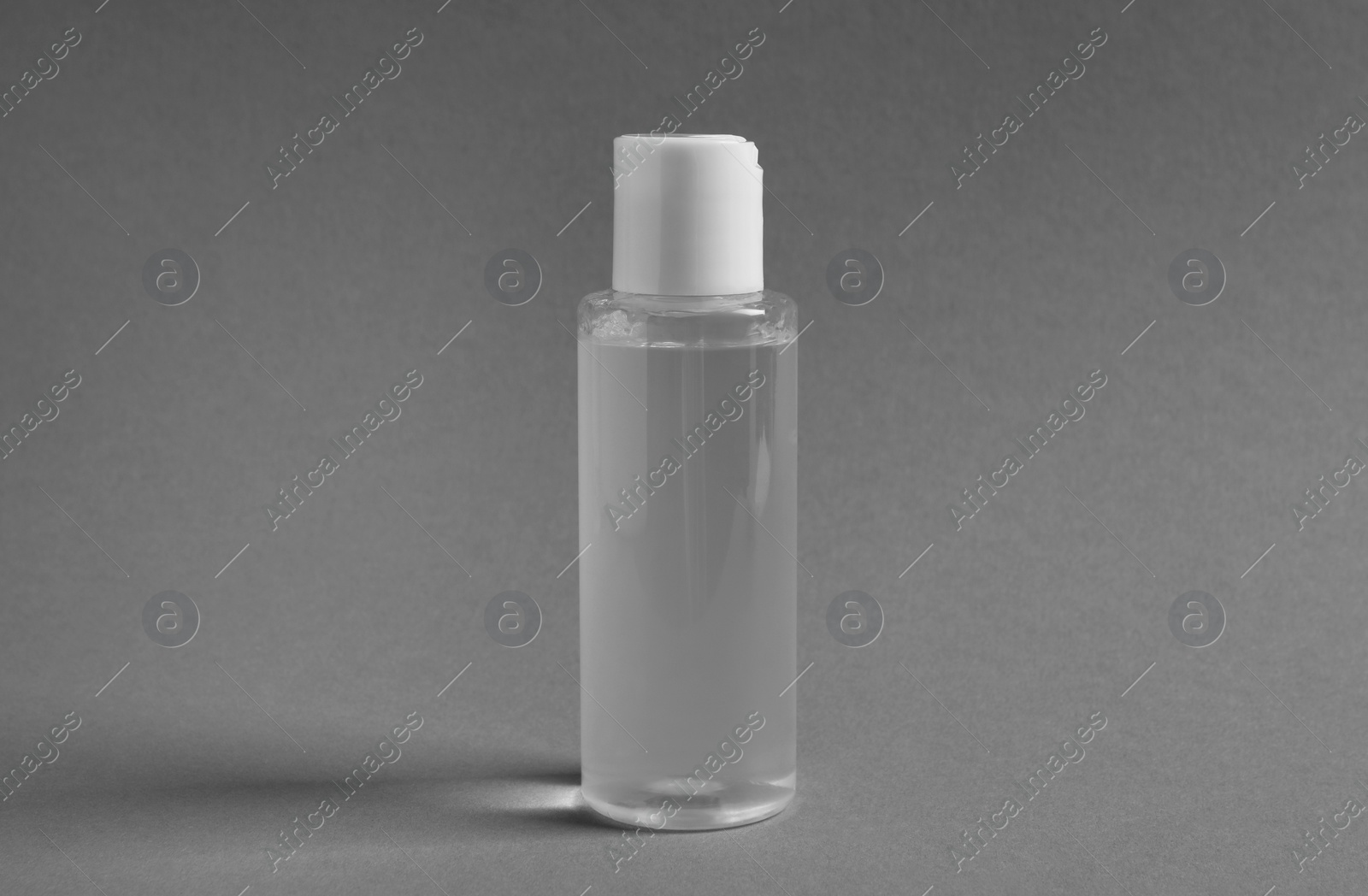 Photo of Transparent bottle with cosmetic product on grey background