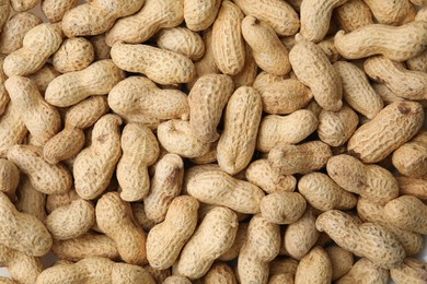 Many fresh unpeeled peanuts as background, top view