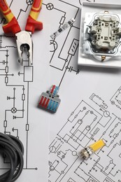 Wiring diagrams, pliers and different electrician's equipment on white table, flat lay