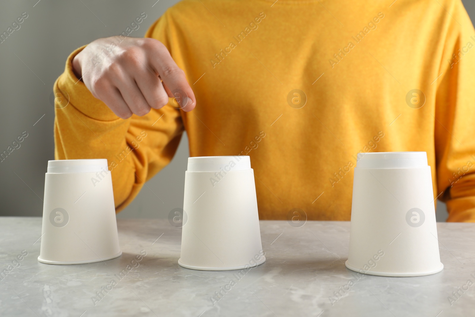 Photo of Man playing shell game at light marble table, closeup