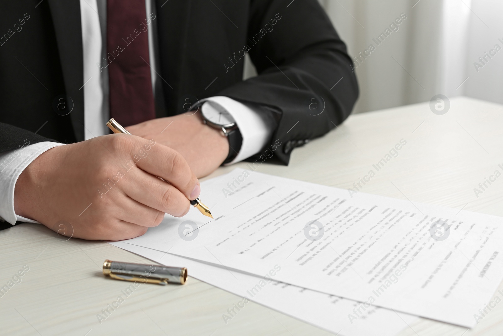 Photo of Notary signing document at wooden table, closeup