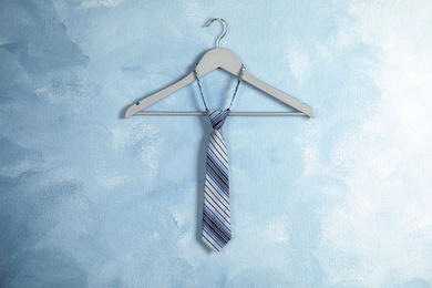 Photo of Tie on wooden hanger against color background