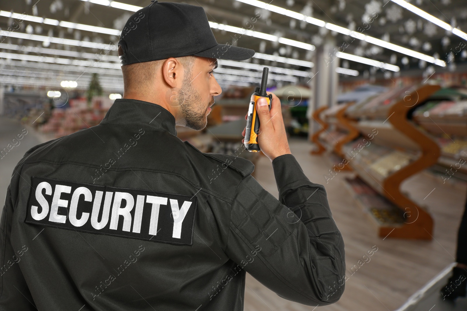 Image of Security guard using portable radio transmitter in shopping mall