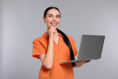 Photo of Thoughtful woman with laptop on light gray background