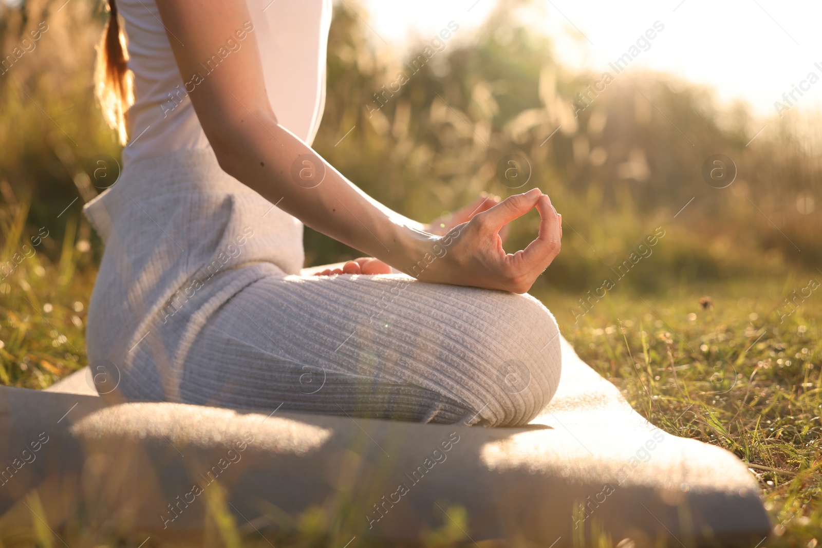 Photo of Woman practicing Padmasana on yoga mat outdoors, closeup. Lotus pose