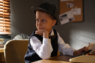 Photo of Cute little detective using typewriter at table in office