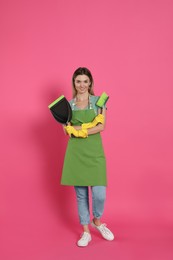 Photo of Young woman with broom and dustpan on pink background