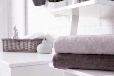 Stack of fresh towels on shelf in bathroom. Space for text