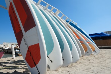 Photo of Rack with colorful paddle boards on sand near sea