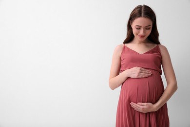 Photo of Beautiful young pregnant woman on light background. Space for text