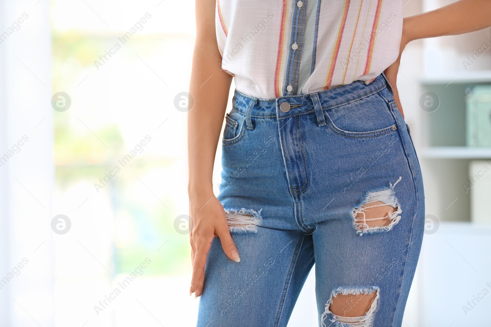 Photo of Young woman in stylish blue jeans indoors