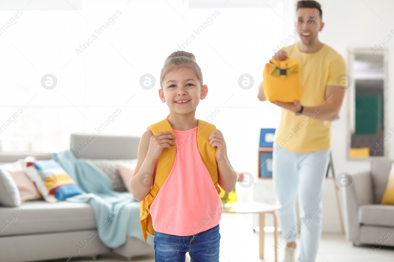 Photo of Young man reminding his little child to take lunch bag as she leaving for school