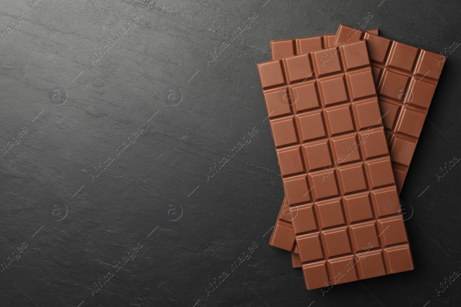 Photo of Tasty chocolate bars on grey table, flat lay. Space for text