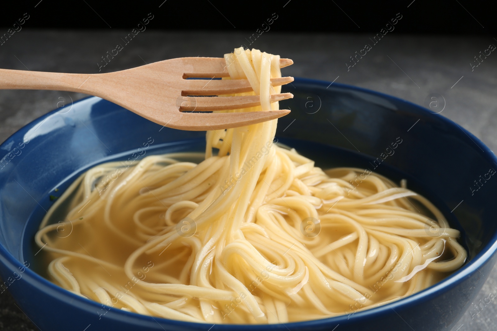 Photo of Eating noodle dish with fork on table, closeup